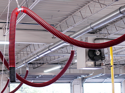 Fume-A-Vent rope and pulley overhead exhaust removal systems installed in an auto dealership workshop.
