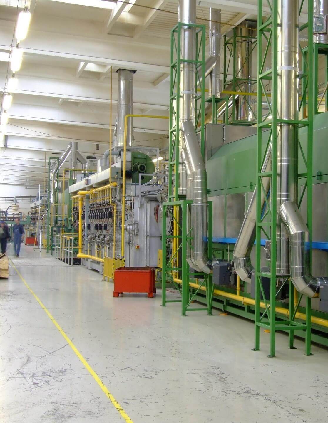 A machine operator and technicians walking through an industrial facility. 