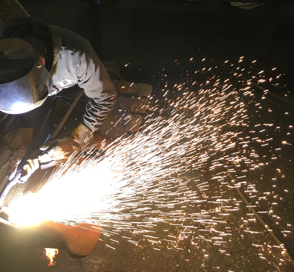 Machine operator working on a project while sparks and smoke are transmitted.