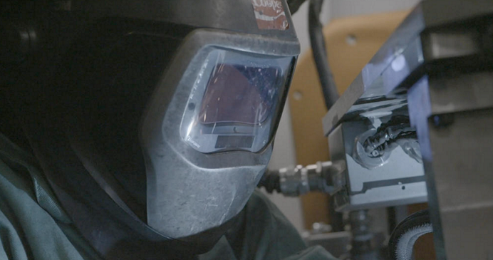 A welder working on an auto part project.