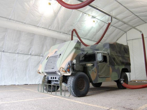 A Humvee in a military tent connected to vehicle exhaust removal system