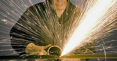 Worker grinding a piece of metal creating sparks