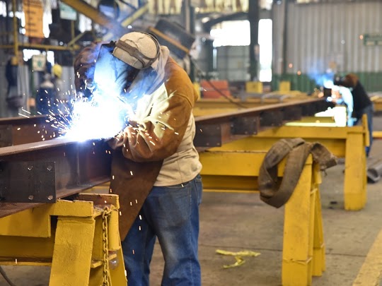 Worker welding on a beam in a welding shop